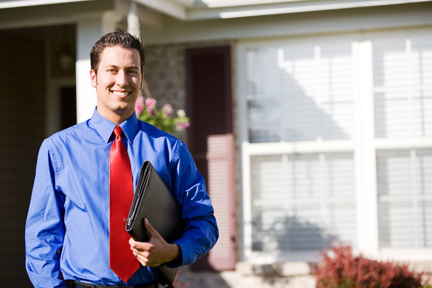 Male real estate agent standing in front of a home